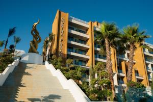 a hotel with palm trees in front of it at Hotel Morina Palace in Dhërmi