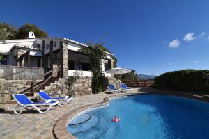 a person in a swimming pool with chairs and a house at Finca Durillo with private Pool in Cómpeta