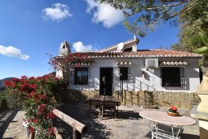 a white house with a table and chairs and flowers at Finca Durillo with private Pool in Cómpeta