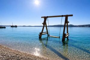 a wooden swing in the water on a beach at Villa Trogir in Trogir