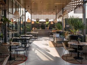 a restaurant with tables and chairs and plants at Novotel Arica in Arica