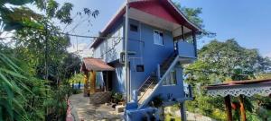 a blue house with a red roof and stairs on it at MountainBrew Homestay in Takdāh