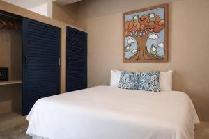a bedroom with a white bed with a tree painting on the wall at Sleepy Gypsea Villa Siargao Swell in Catagnan