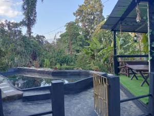 a pool in a backyard with a fence and a table at MountainBrew Homestay in Takdāh