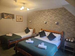 two beds in a hotel room with towels on them at Tailrace Inn in Kinlochleven