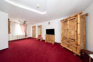 a living room with a red carpet and a tv at Pensiunea Rosenau in Râşnov