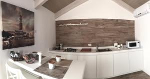 マテーラにあるEssenze Home Galleryの白いキャビネットと木製の壁が備わるキッチン