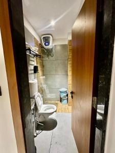 a bathroom with a toilet and a tv on the wall at Spacious 2BHK Group Stay in Vijay Nagar, Indore in Indore