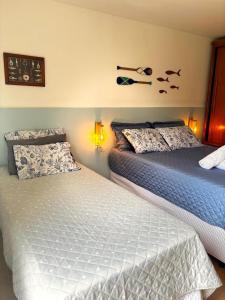 a bedroom with two beds and a shelf with birds on the wall at Suíte aMAR in São Pedro da Aldeia