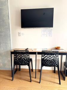 a desk with two chairs and a television on a wall at Suíte aMAR in São Pedro da Aldeia +36 photos
