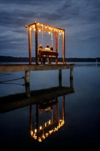 two people sitting on a bench on a pier with lights at Akwaba Lodge Island Boutique Hotel in The Gap