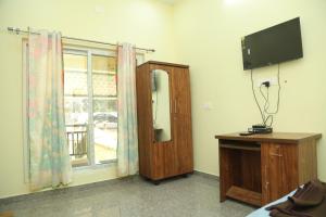 a room with a television and a dresser and a window at serene cottage in Yelagiri