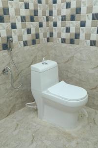 a white toilet in a bathroom with a tile wall at serene cottage in Yelagiri +15 photos