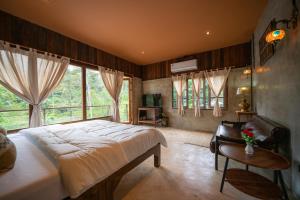 a bedroom with a large bed in a room with windows at Cozy Home Saluang in Ban Lua Ka