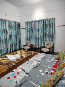a room with two beds and two chairs and curtains at The Rest Nest in Gorakhpur
