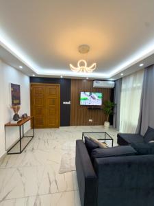 a living room with a couch and a tv at Bel appartement a Yaoundé Bastos in Yaoundé
