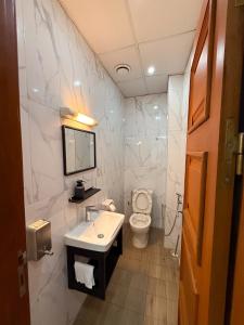 a white bathroom with a sink and a toilet at Bel appartement a Yaoundé Bastos in Yaoundé +6 photos