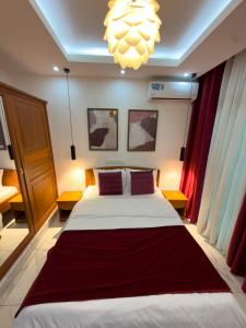 a bedroom with a large bed and a chandelier at Bel appartement a Yaoundé Bastos in Yaoundé