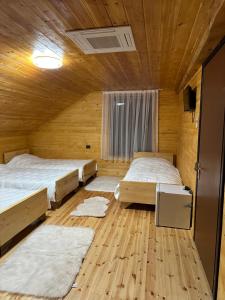 two beds in a room with wooden walls and wooden floors at Bujtina Alpine Vanat in Bele