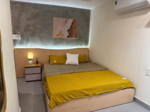 a small bedroom with a bed with a yellow blanket at Dana Home MT in Danang