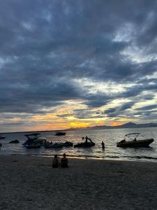a group of people sitting on a beach with boats in the water at Chalé da Ilha in Guaraqueçaba +4 photos