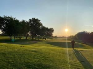 a man walking on a golf course at sunset at Tee Off House - Parys Golf and Country Estate in Parys