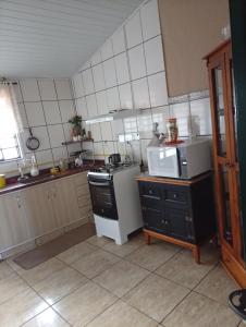 a kitchen with a stove and a microwave at Quarto Suite & Cozinha in Piraju