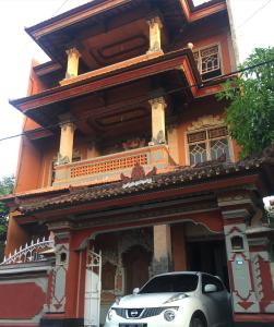 Ratih Bali Hostel في دينباسار: سيارة بيضاء متوقفة أمام مبنى