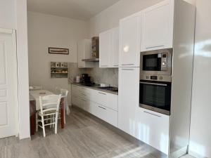 a white kitchen with white cabinets and a table at Chianti 22 in Poggibonsi