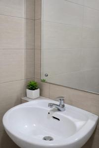 a white sink in a bathroom with a mirror at Soft Reset Room by YOMAIN in Kemirimuka Tiga