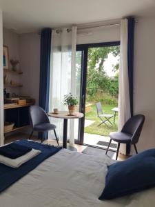 a bedroom with a bed and a table and chairs at Escale à Kergrenn in Fouesnant