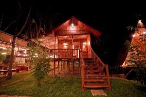 a wooden house with a staircase leading to it at night at Bali Bamboo Resort in Padinjarathara