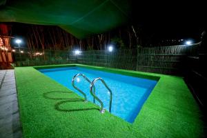 a swimming pool at night with green grass at Bali Bamboo Resort in Padinjarathara