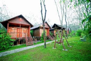 a log cabin with a swing and a playground at Bali Bamboo Resort in Padinjarathara