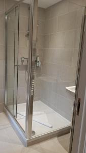 a bathroom with a shower with a glass door at Cottages at the Lugger in Portloe +28 photos