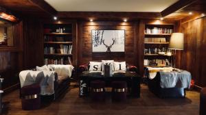 a library with two chairs and a table and bookshelves at Hotel Tsanteleina in Val-d'Isère +51 photos