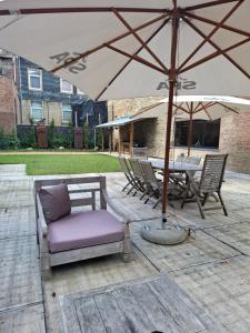 a patio with an umbrella and a table and chairs at L'entrepôt Spadois in Spa
