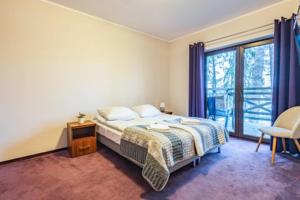 a bedroom with a bed and a large window at Apartamenty Niegocin in Wilkasy