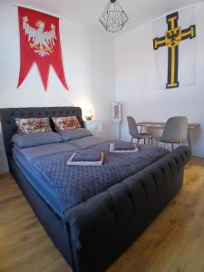 a bed in a room with a cross on the wall at Apartamenty Zakonne "Apartament Komtura" in Malbork