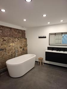 a white bath tub in a bathroom with a brick wall at L'entrepôt Spadois in Spa +69 photos