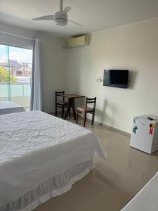 a bedroom with a bed and a table and a tv at Hotel Aconchego da Vila A in Saquarema