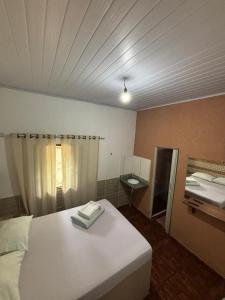 a bedroom with a white bed and a mirror at Pouso do Carmo in Pirenópolis