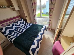 a small bedroom with a bed and a window at Lilly Luxury Hot Tub Caravan - theluxurycaravan - GV109 Grange Leisure Park in Mablethorpe