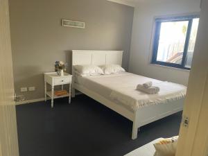 a bedroom with a white bed and a window at Boyne island beach house in Boyne Island