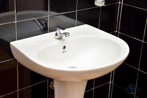 a white sink in a bathroom with black tiles at The Change Hotel in Kandy +58 photos