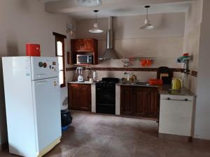 a kitchen with a white refrigerator and wooden cabinets at Casa Verdes del Malka in Tilcara