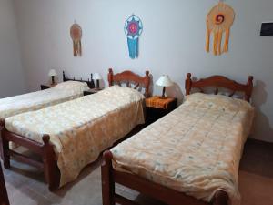 a bedroom with two beds and a wall with some decorations at Casa Verdes del Malka in Tilcara