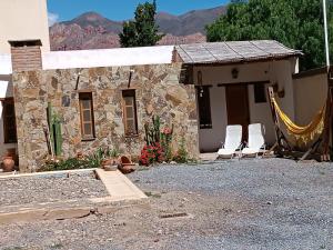 a stone house with a hammock in front of it at Casa Verdes del Malka in Tilcara
