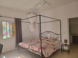 a bedroom with a black canopy bed with a floral bedspread at Le Dolmen de Mbour in Mbour +69 photos