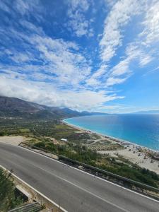 an empty road next to a beach with the ocean at Petrit apartament in Qeparo